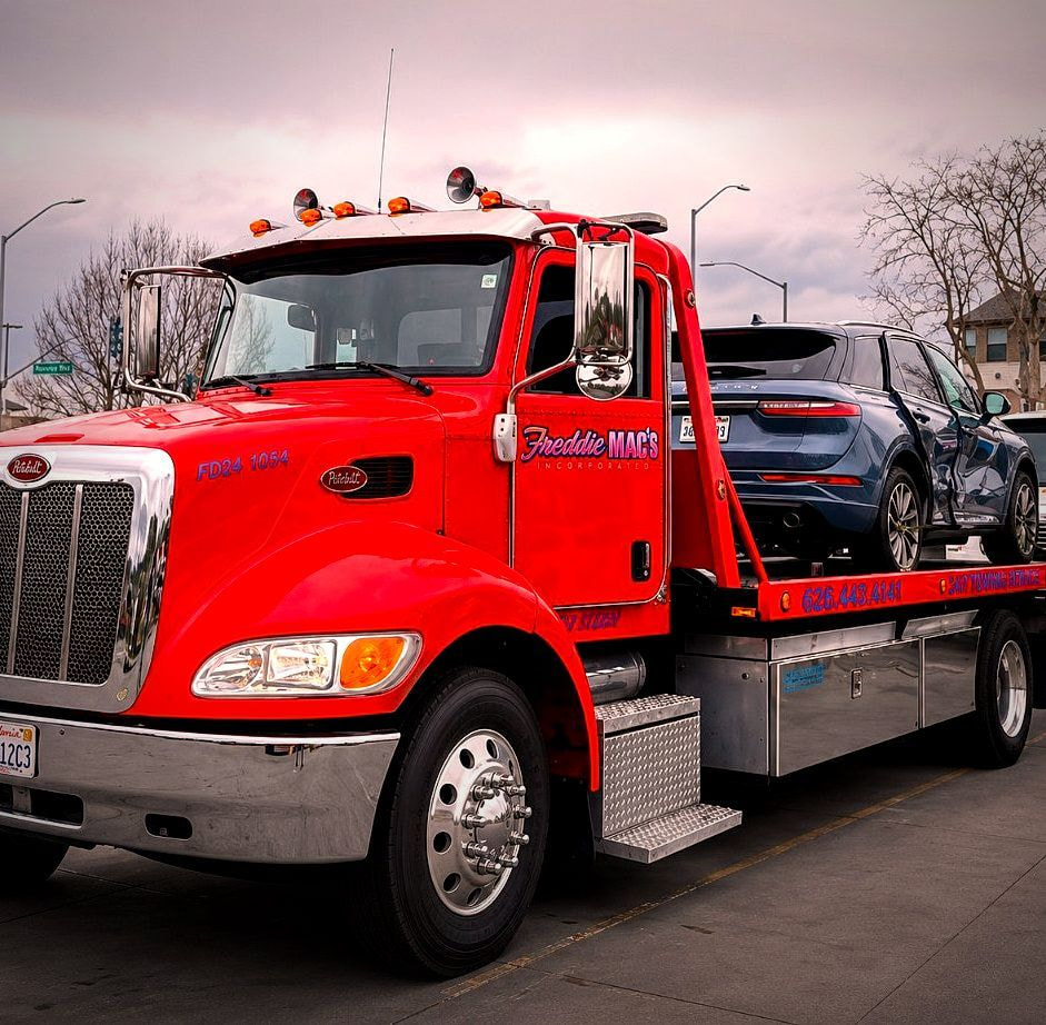 Freddie Mac's red Peterbilt flatbed tow truck with a vehicle secured on the bed